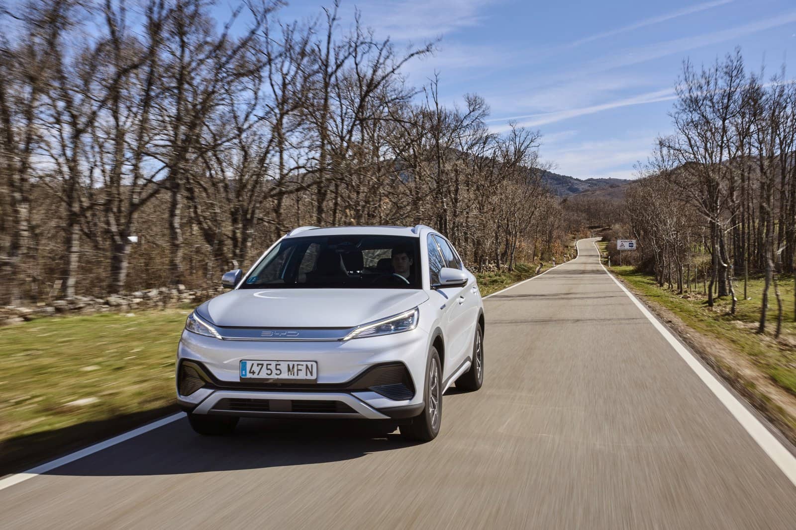 BYD Atto3 avanzando por una carretera rodeada de árboles.