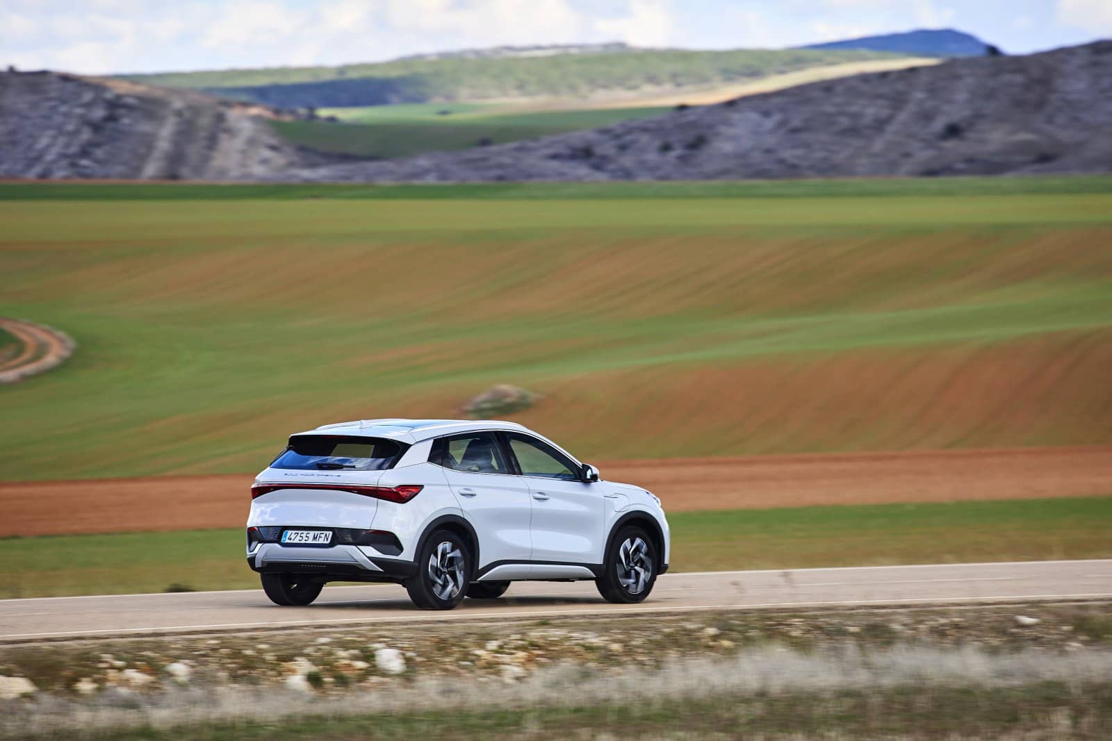 Vista dinámica lateral del BYD Atto3 en carreteras rurales.