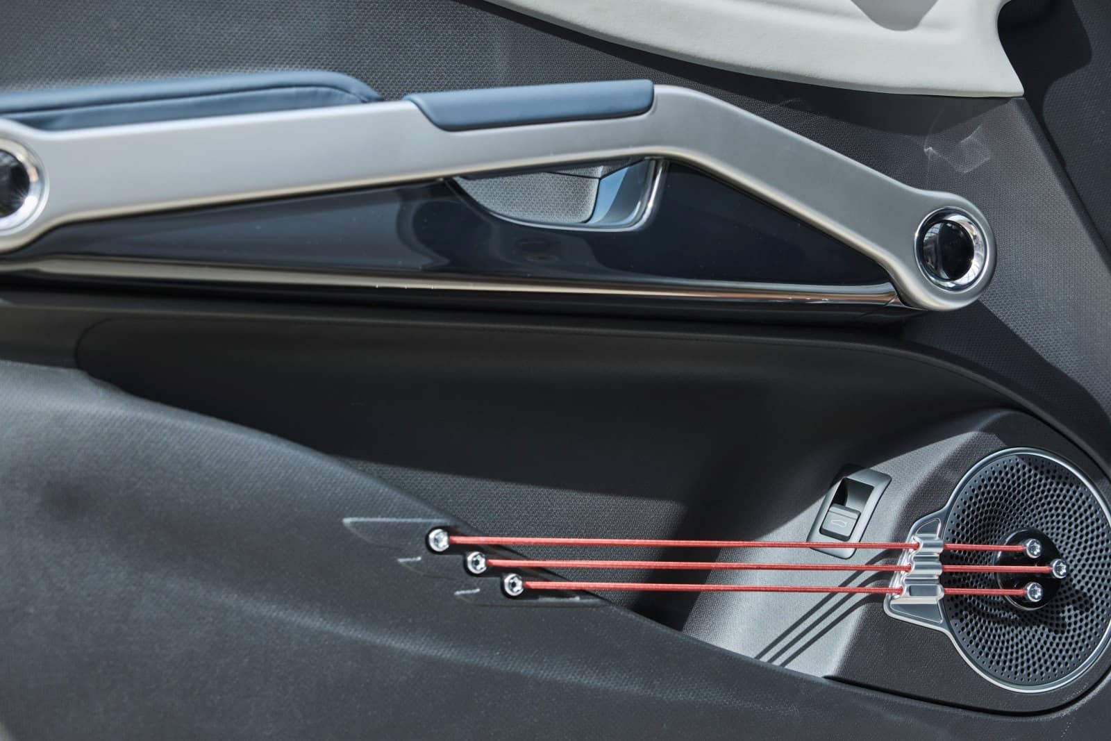 Detalle del diseño del altavoz en la puerta con iluminación ambiental roja.