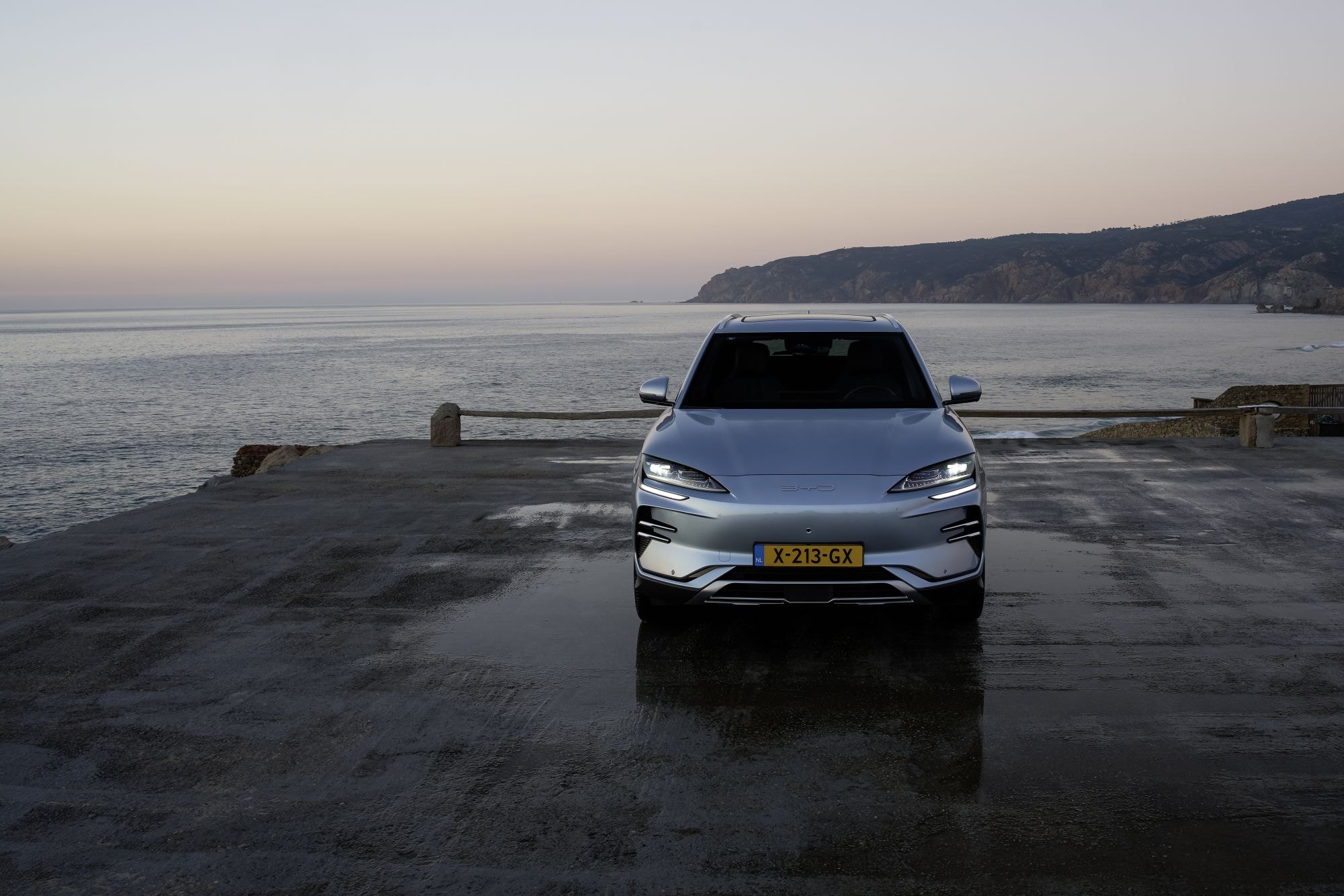 Vista frontal del SUV sobre el muelle con el océano de fondo.
