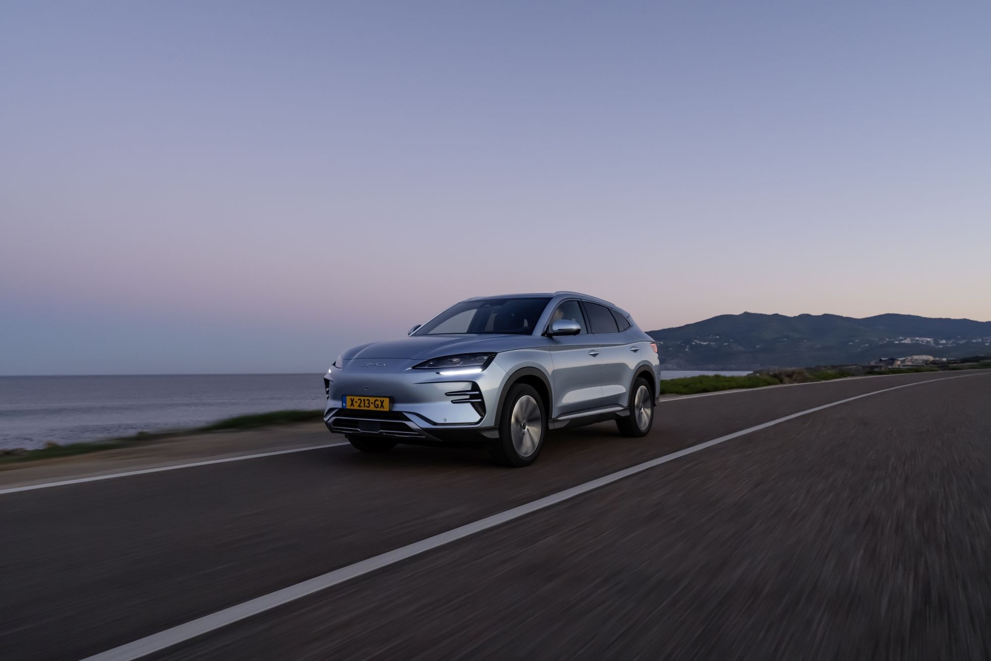 El BYD Seal U avanzando por una carretera costera en un atardecer pintoresco.