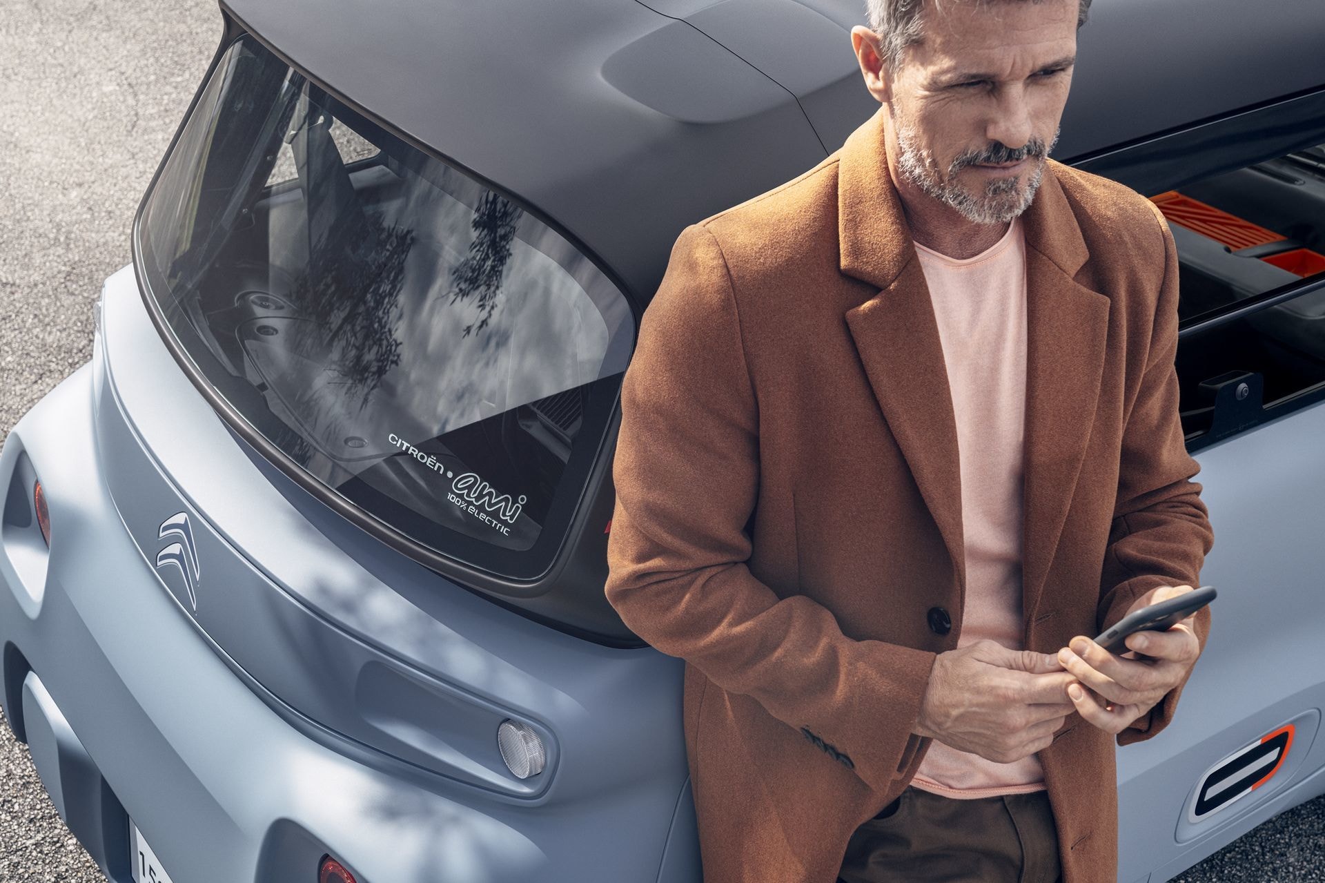 Detalle de la zona trasera del Citroën AMI con hombre utilizando un smartphone.