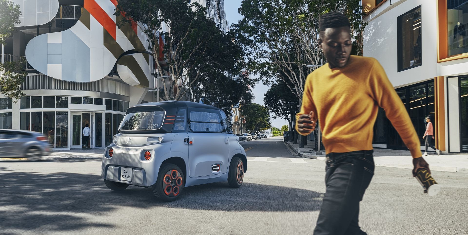 El Citroën AMI en la ciudad, con un peatón al lado, enfatiza su escala.