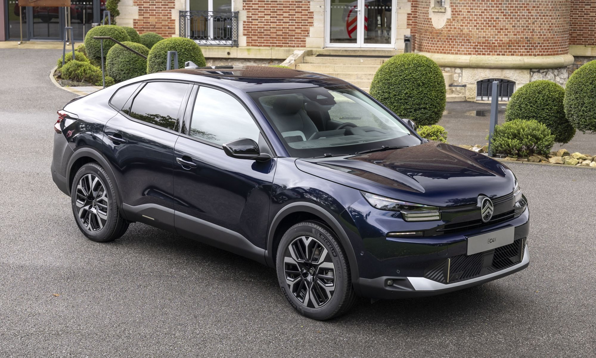 Citroën C4 X estacionado cerca de un punto de carga, indicando su naturaleza eléctrica.