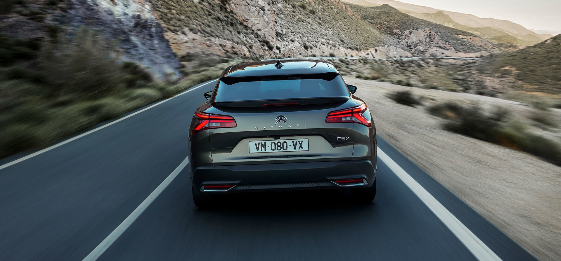 Perspectiva trasera del Citroën C5 X destacando su musculosa silueta en carretera.