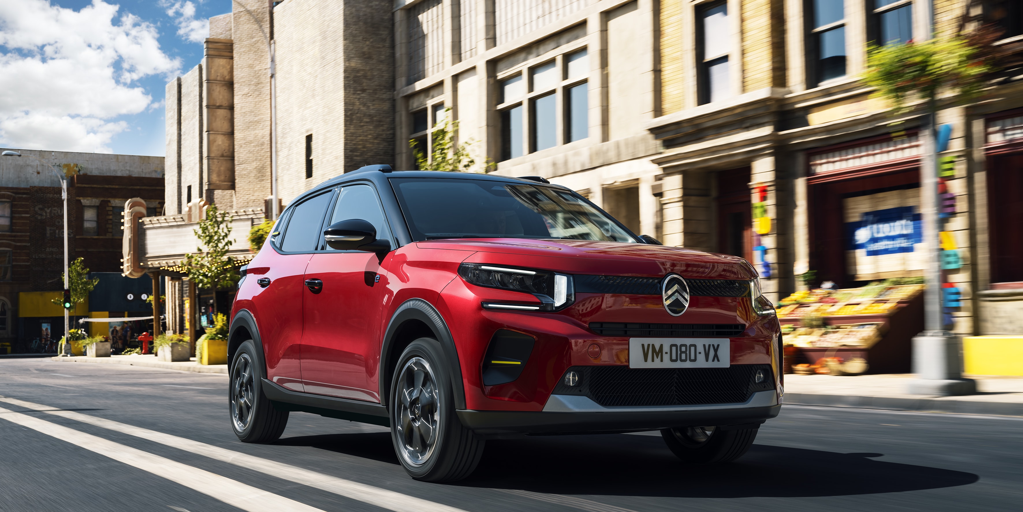 Citroën ë-C3 en movimiento lateral, integrado en el paisaje urbano con un diseño eléctrico.