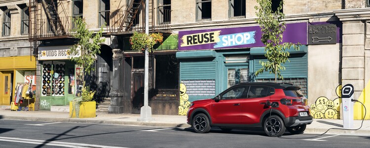 Perspectiva lateral del Citroën ë-C3 en ambiente urbano que muestra su diseño adaptativo. Perspectiva lateral del Citroën ë-C3 en ambiente urbano que muestra su diseño adaptativo.