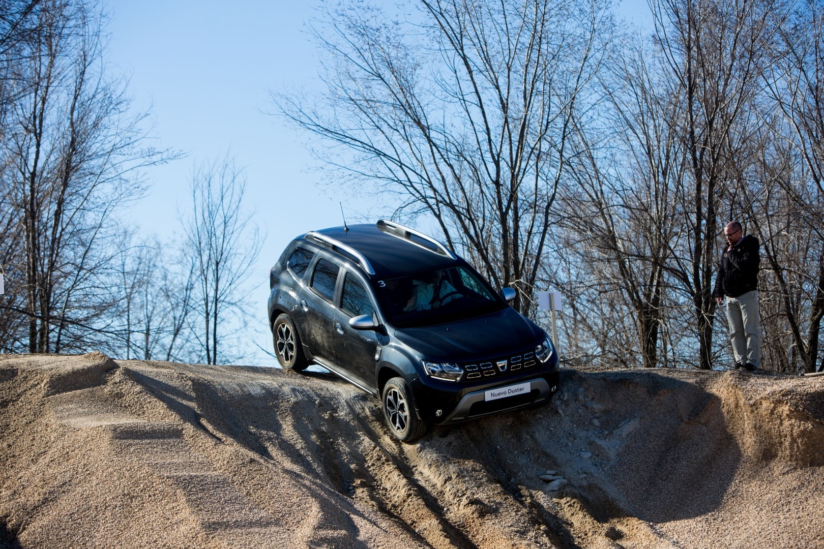 Dacia Duster en descenso mostrando sus capacidades todoterreno con espectadores al fondo.