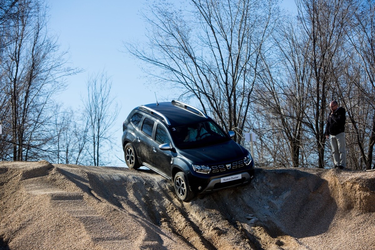 Dacia Duster en descenso mostrando sus capacidades todoterreno con espectadores al fondo. Dacia Duster en descenso mostrando sus capacidades todoterreno con espectadores al fondo.