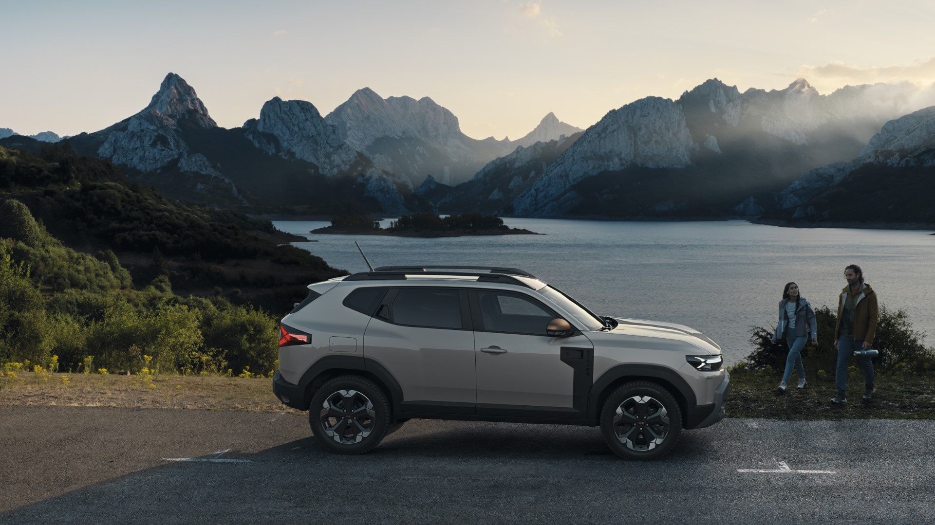 Lateral del Dacia Duster con personas al fondo, subrayando su contexto familiar y de ocio junto al lago.