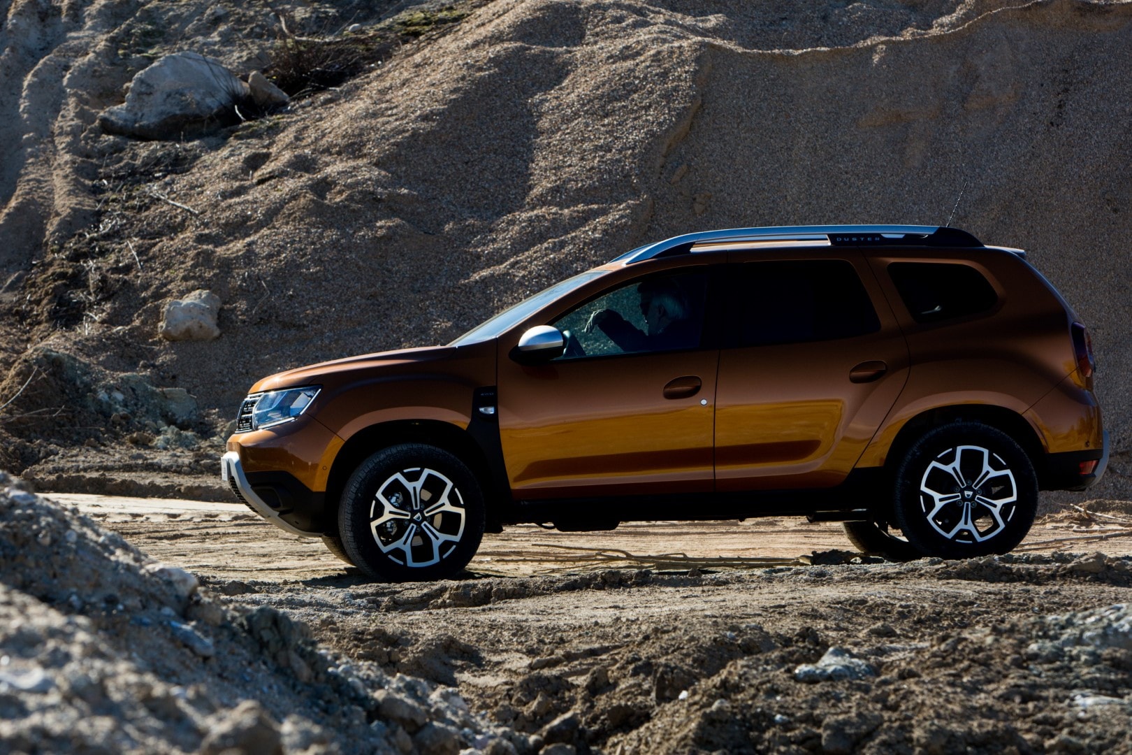 Perfil del Dacia Duster realzando su diseño aventurero en terreno rocoso.