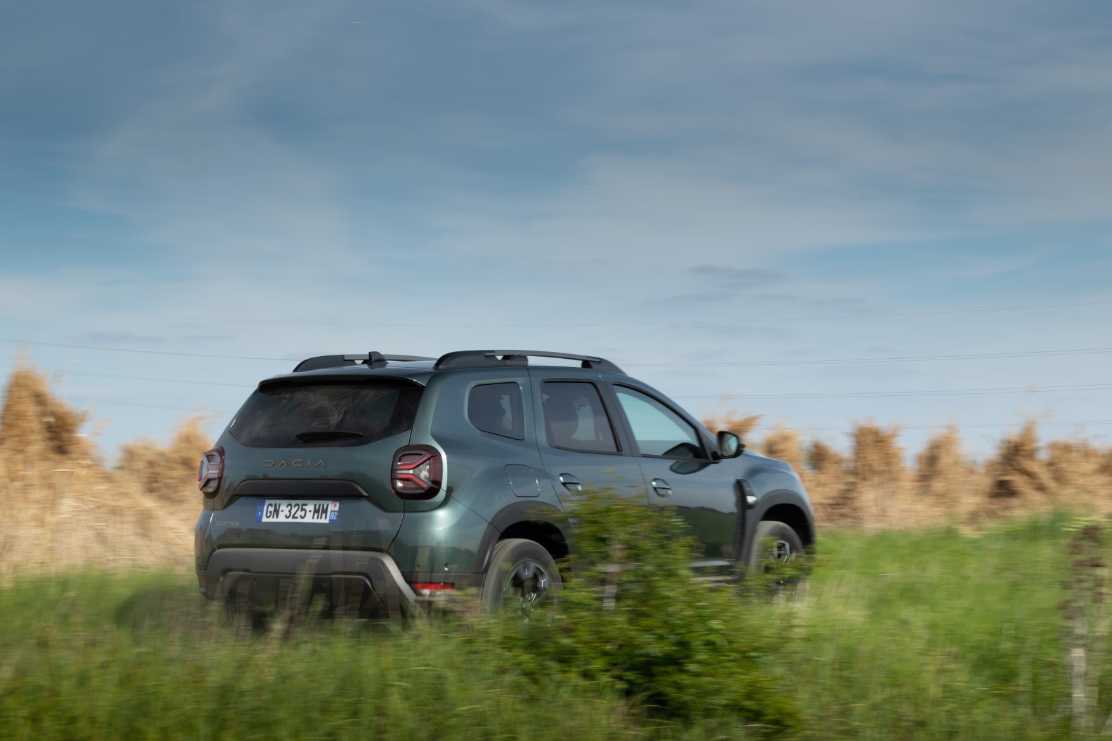 Vista lateral y trasera del Dacia Duster en terreno de campo, ilustrando su perfil y capacidades off-road.