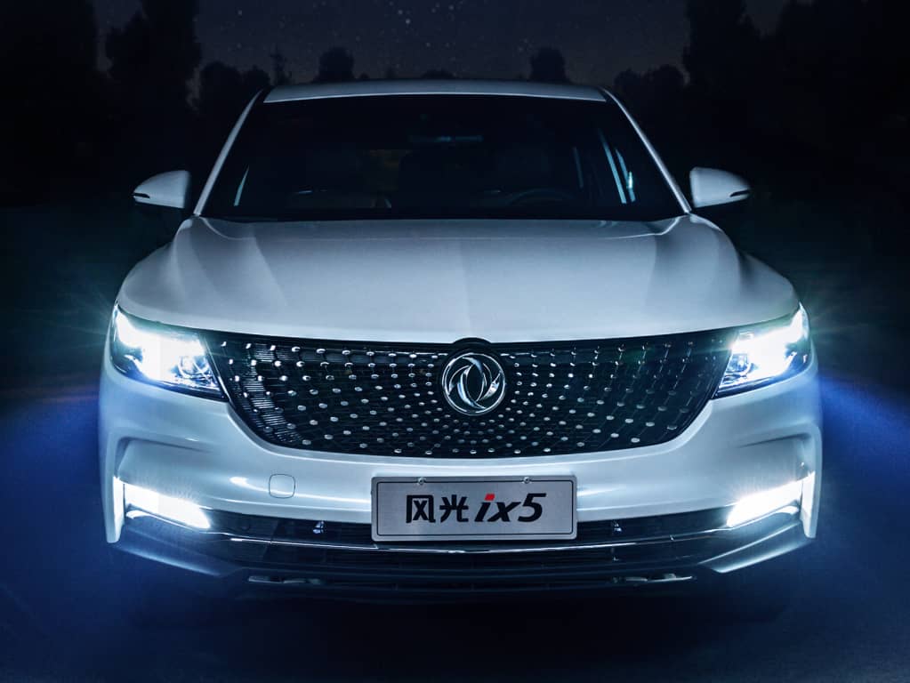 El DFSK F5 iluminado en la noche resalta su diseño frontal.