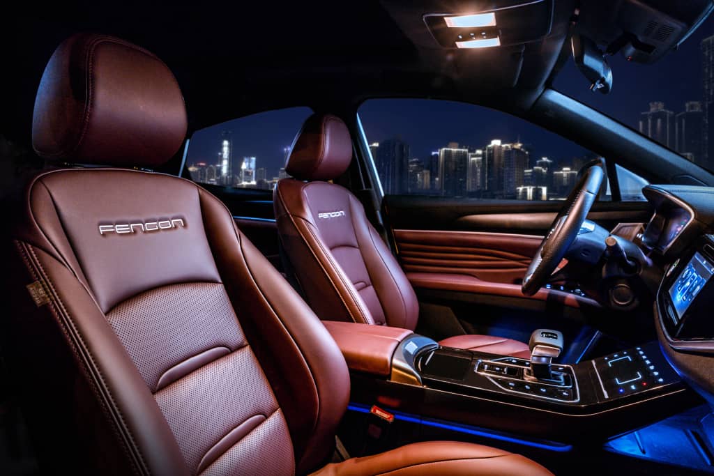 Interior nocturno del DFSK F5 con enfoque en los asientos y sistema de entretenimiento.