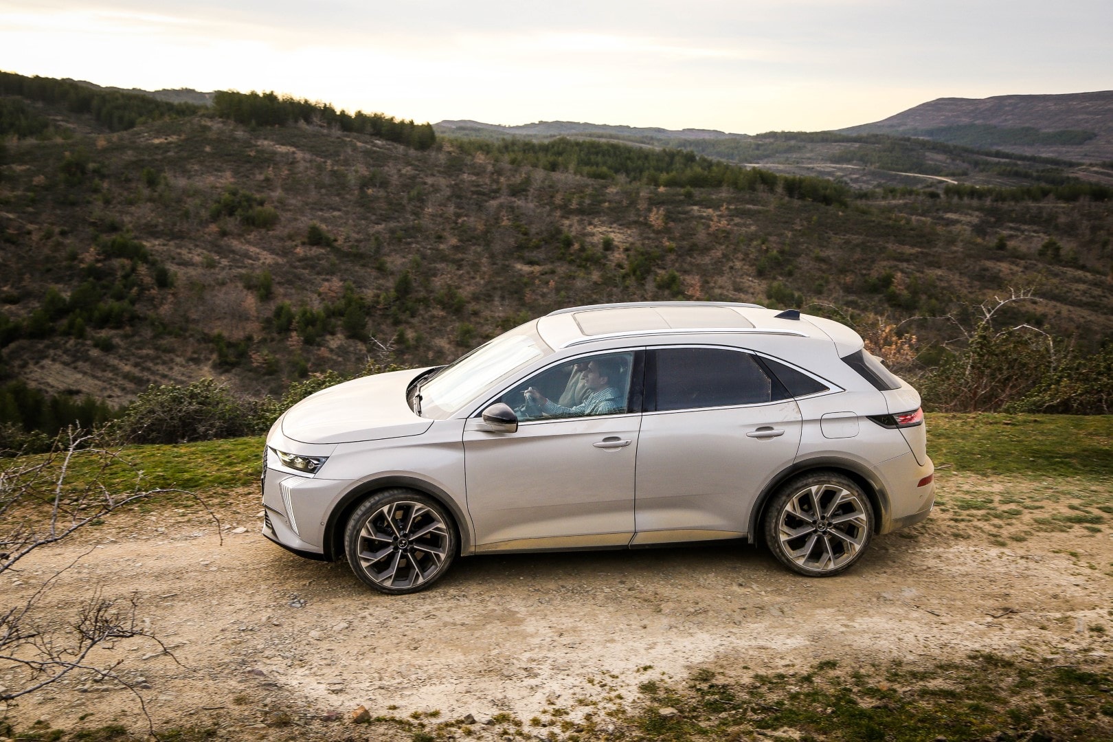 Vista lateral con ángulo elevado del DS7 Híbrido en un entorno natural.