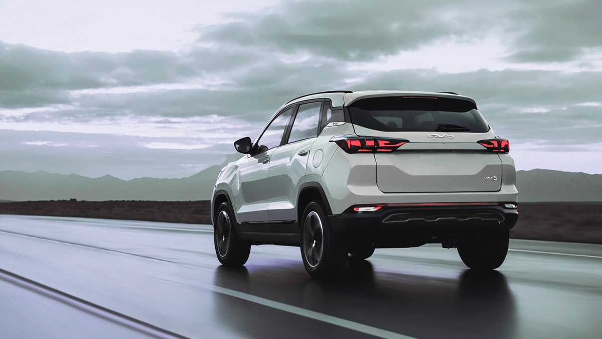 Vista trasera lateral del EVO 5 en movimiento, destacando sus luces traseras y spoiler.