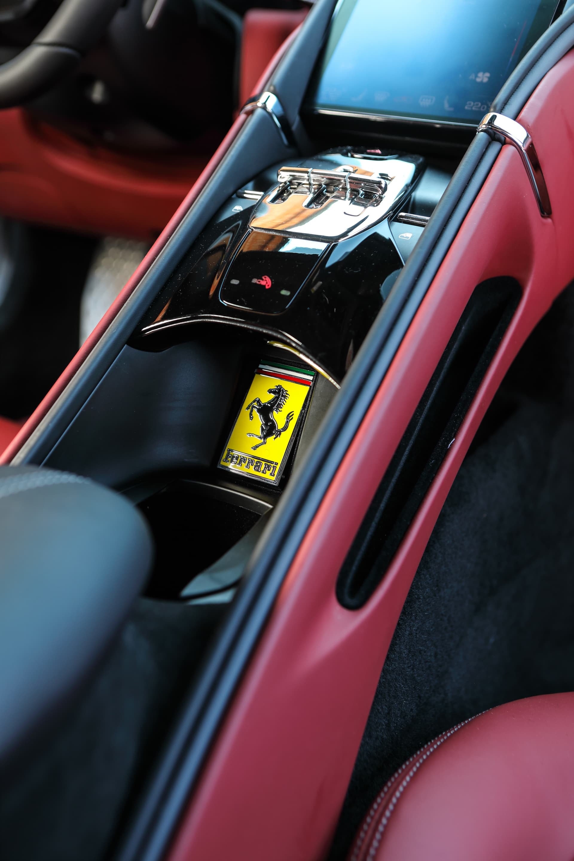 Consola central con selector de cambios y logo Ferrari, diseño sofisticado y elegante.