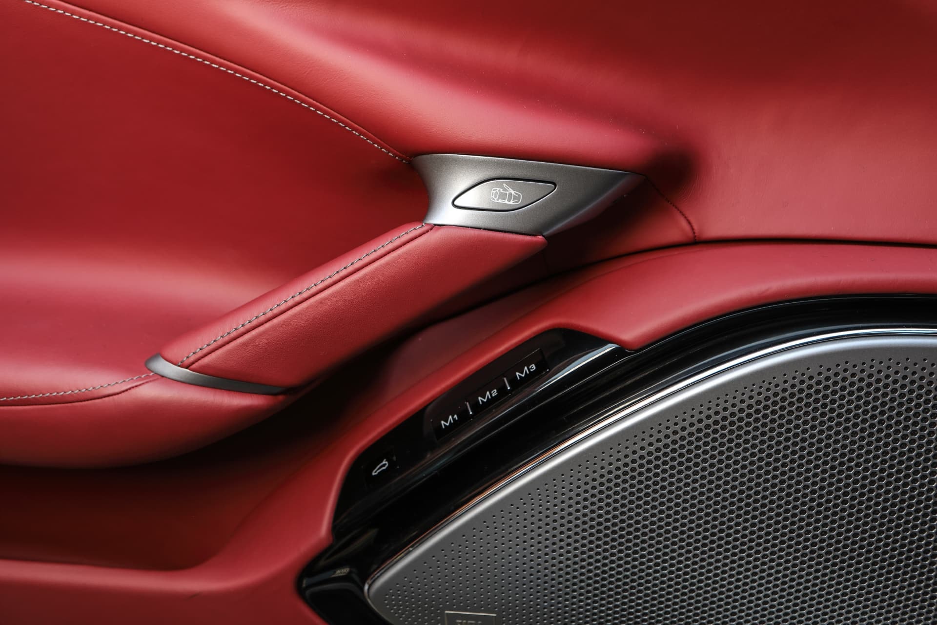 Detalle de la puerta con acabados en cuero rojo y controles integrados.