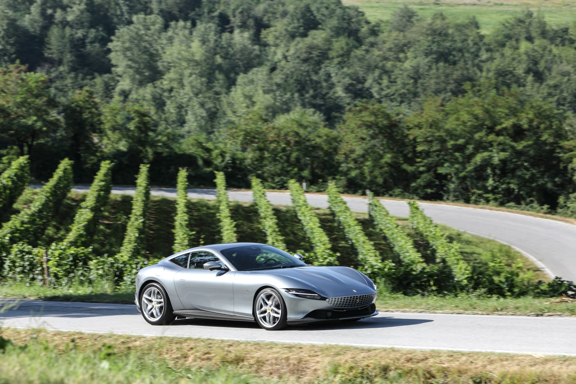 Vista dinámica frontal del Ferrari Roma adelantando en carretera, transmite velocidad y elegancia.