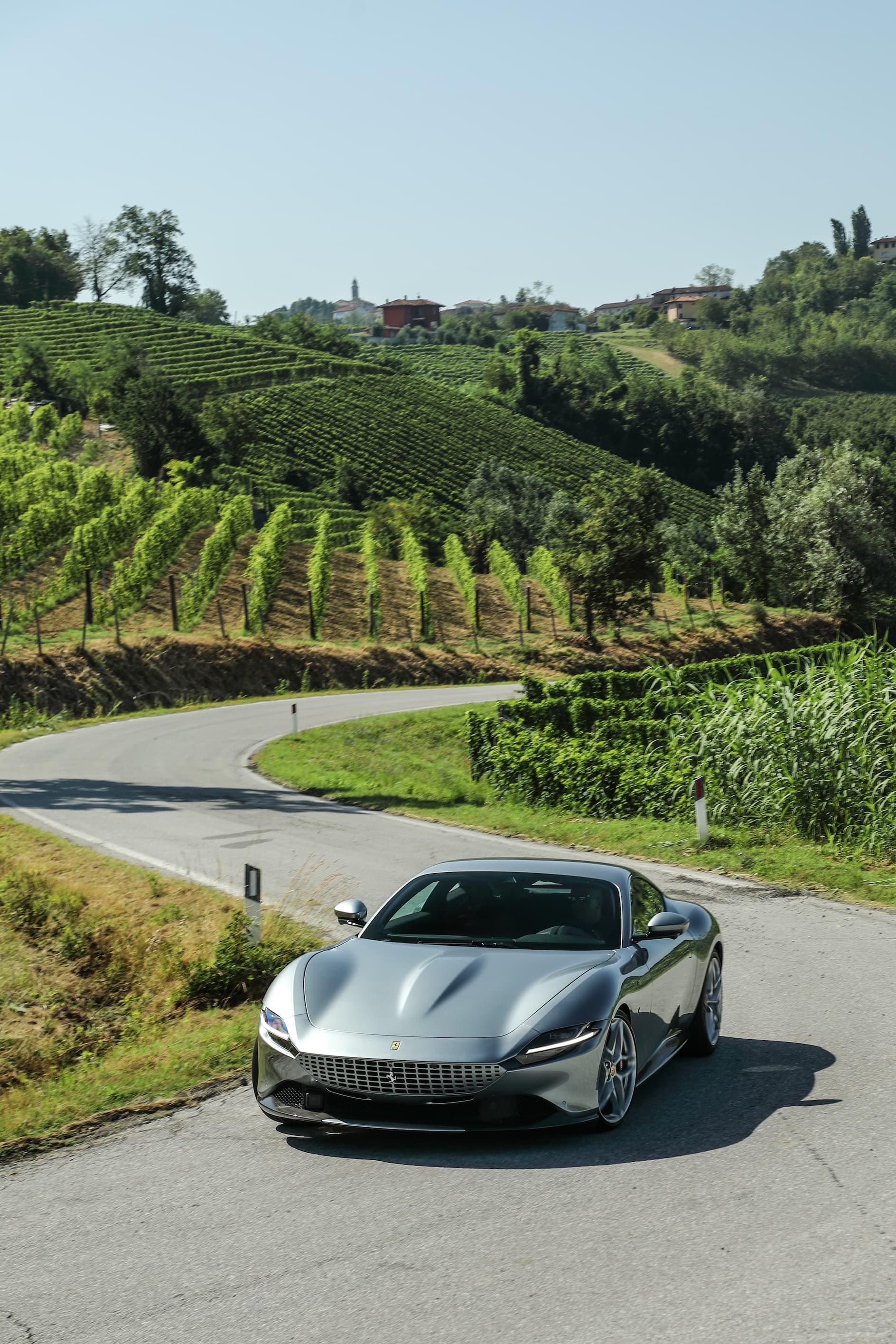 Ferrari Roma en carretera rodeada de viñedos, integrándose con el paisaje.