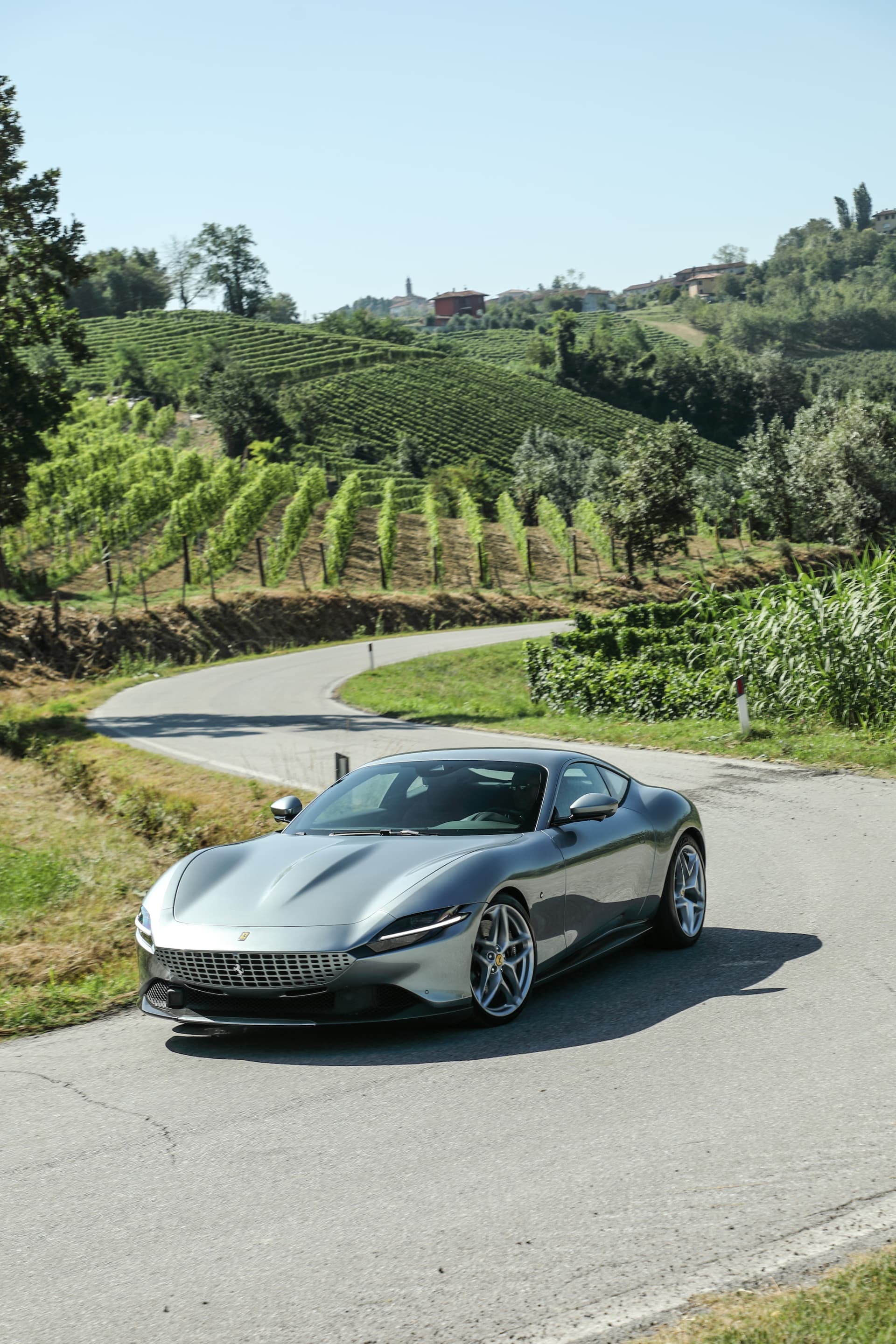 El Ferrari Roma luce su elegante diseño frontal y lateral en un entorno natural.