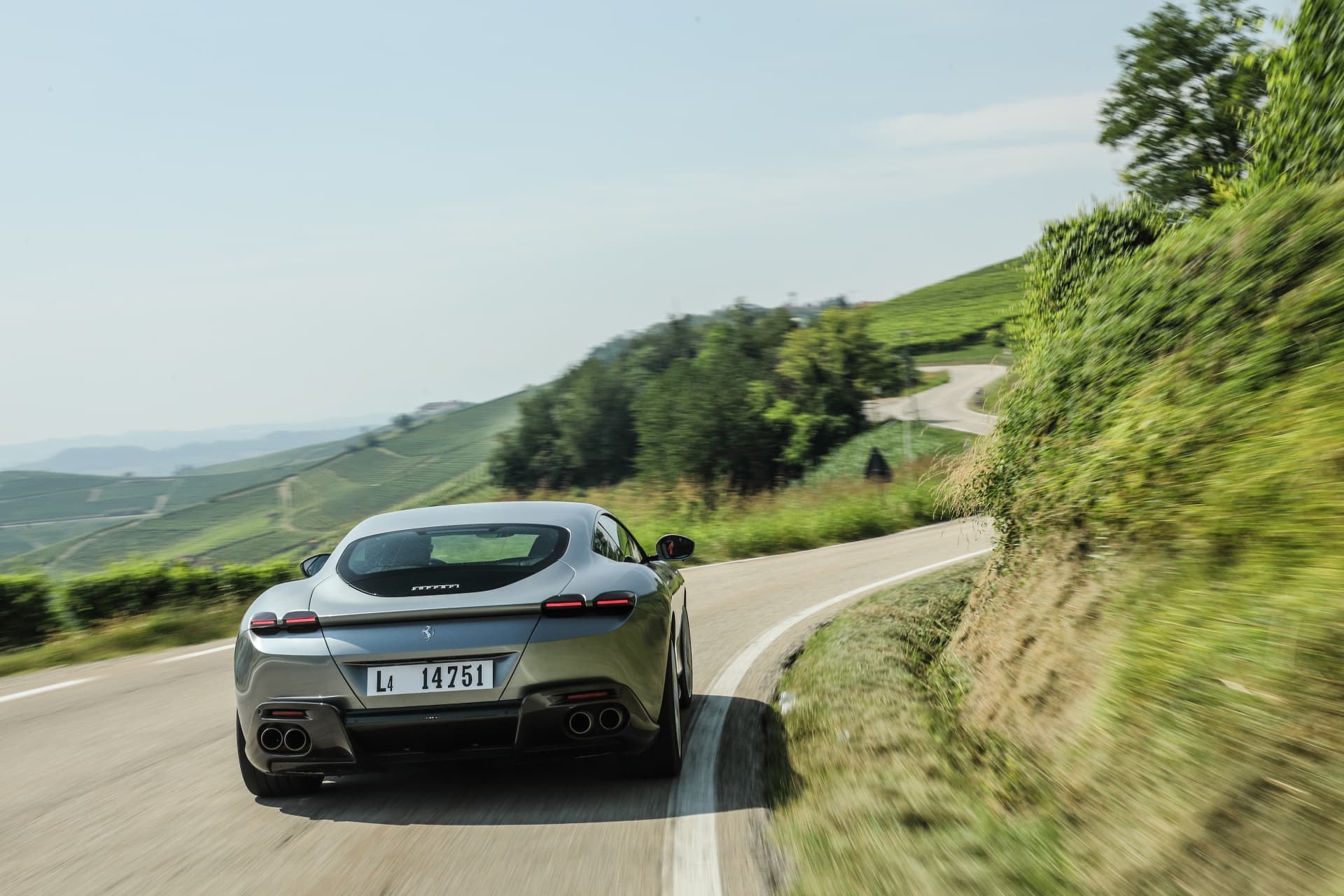 Perspectiva trasera del Ferrari Roma en carretera, evidenciando sus líneas deportivas.