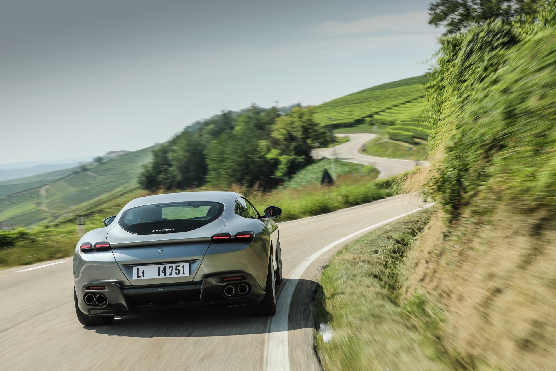 Vista trasera del Ferrari Roma en carretera revelando su poderoso sistema de escape.