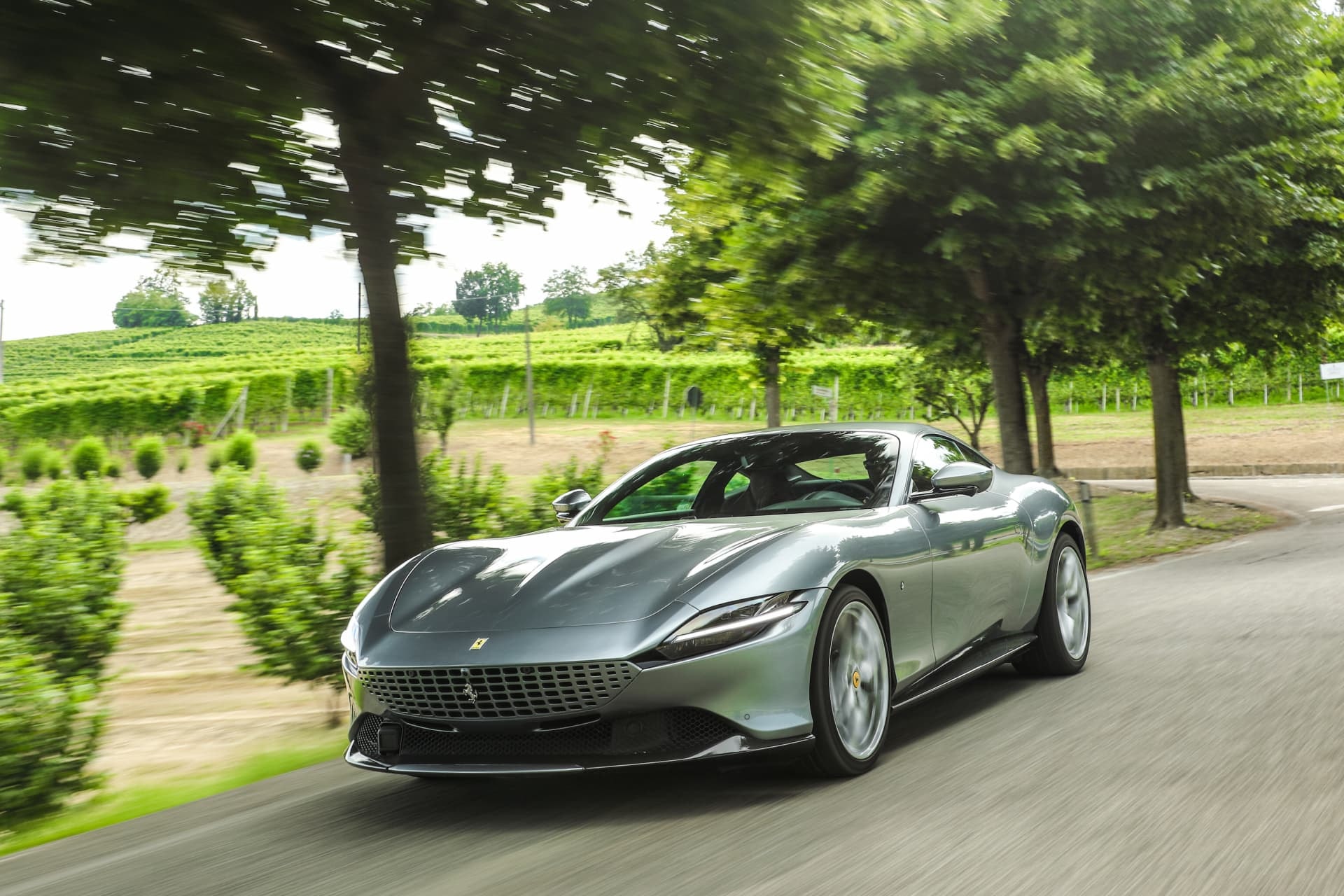 Lateral del Ferrari Roma en movimiento, complementado por la naturaleza verde.