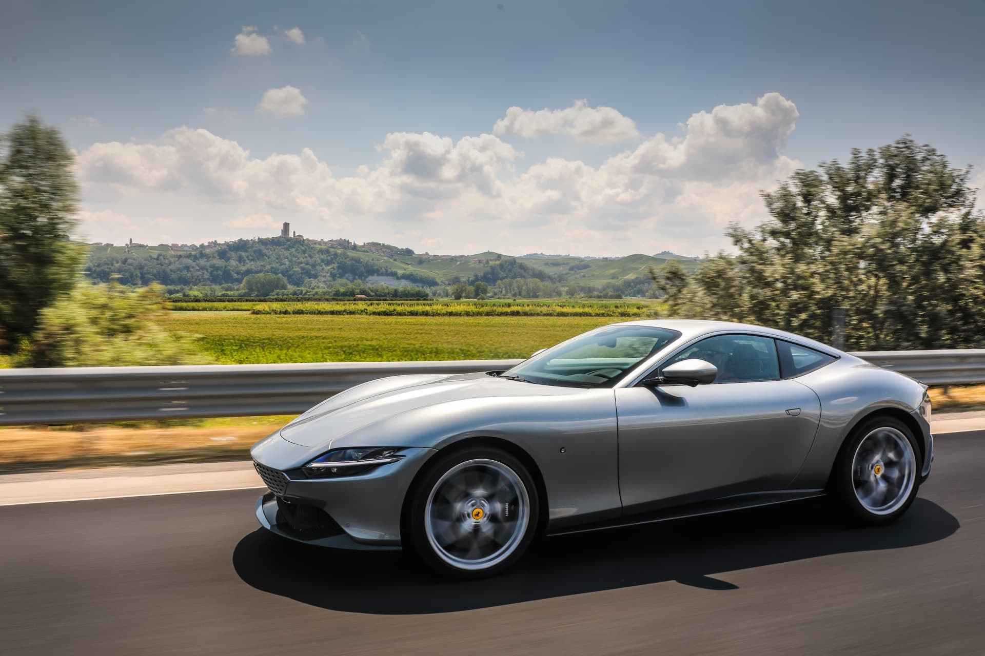 Lateral del Ferrari Roma en acción con un paisaje vitivinícola al fondo
