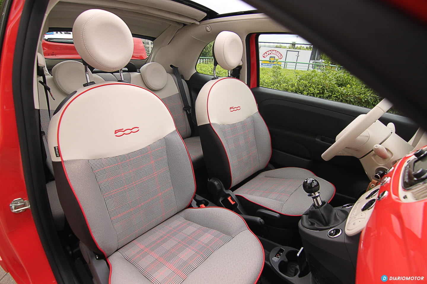 Asientos delanteros del Fiat 500 con tapizado en tela, combinando rojo y gris.