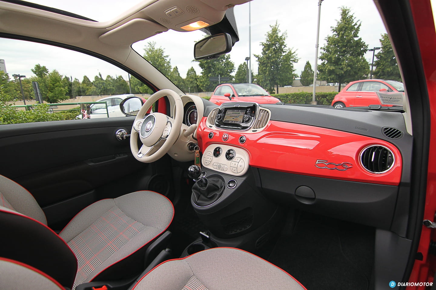 Tablero interior del Fiat 500 con acentos en rojo, volante y panel central visible.