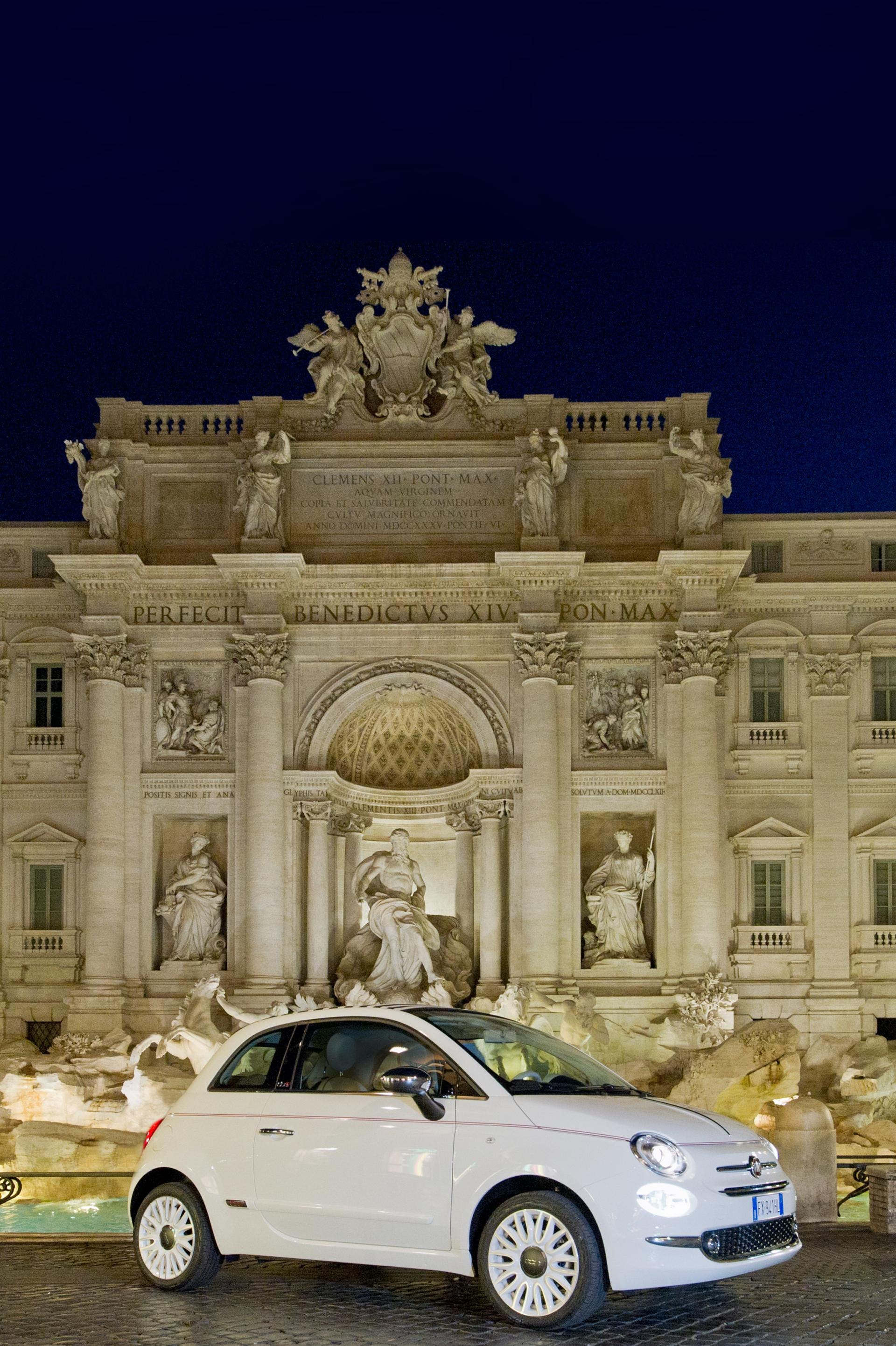 Vista nocturna del Fiat 500C blanco frente a la Fontana di Trevi, iluminación que resalta sus líneas.