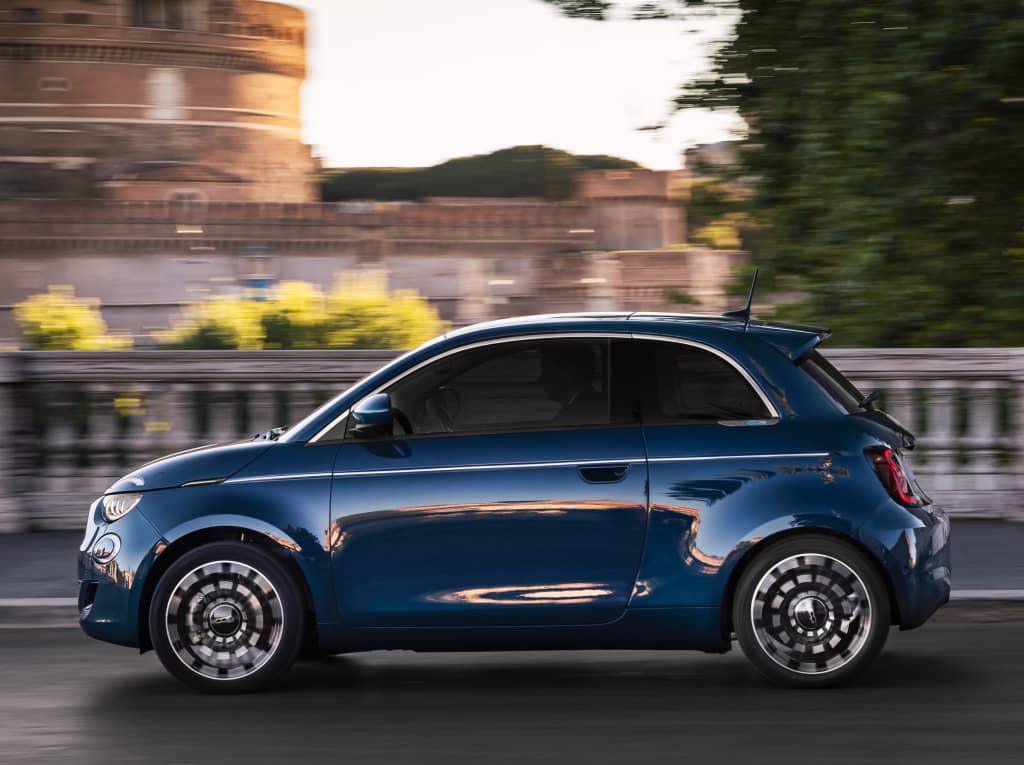 Vista lateral en movimiento, destacando las llantas y perfil urbano del Fiat 500e.
