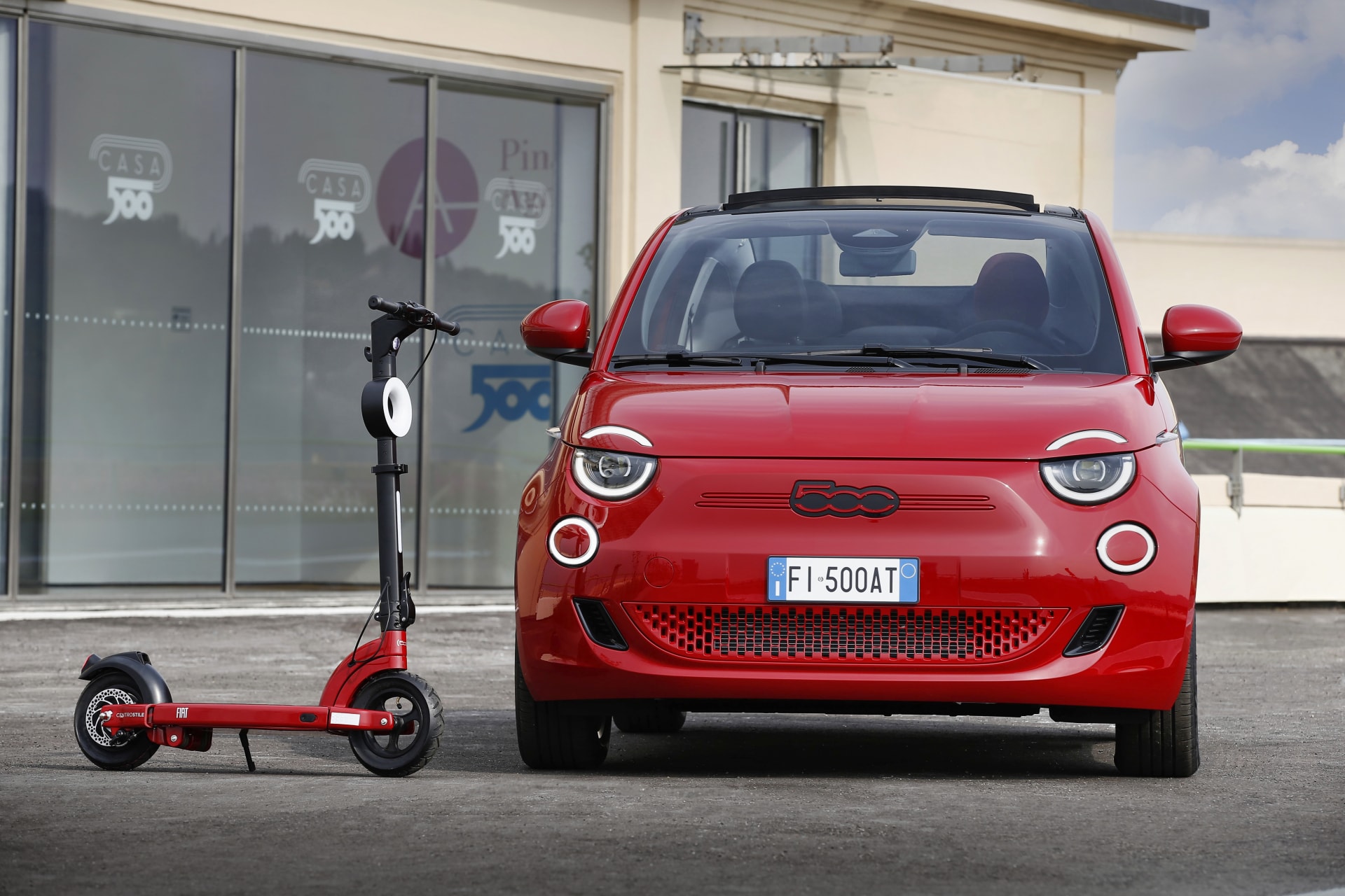 Fiat 500e rojo acompañado de un patinete eléctrico a juego.