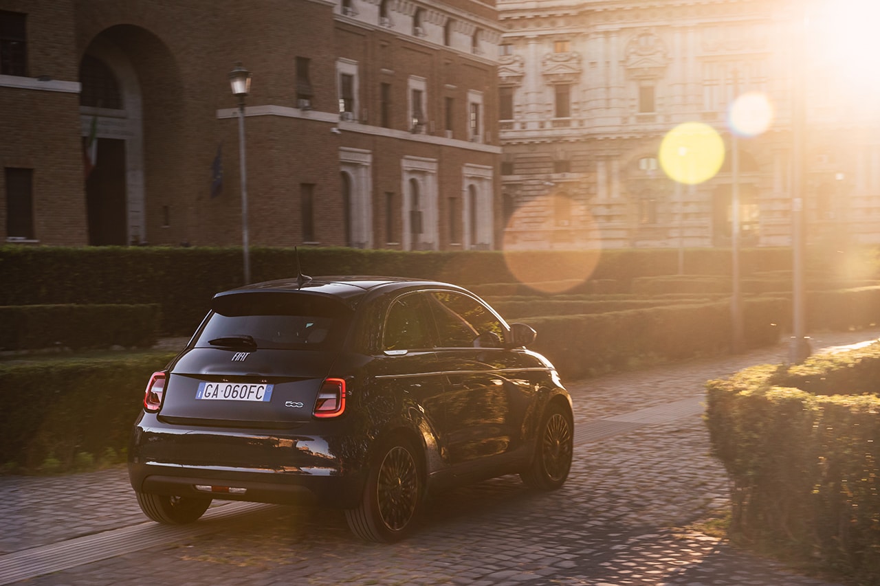 Fiat 500e capturado al atardecer, destacando la silueta trasera y el techo.