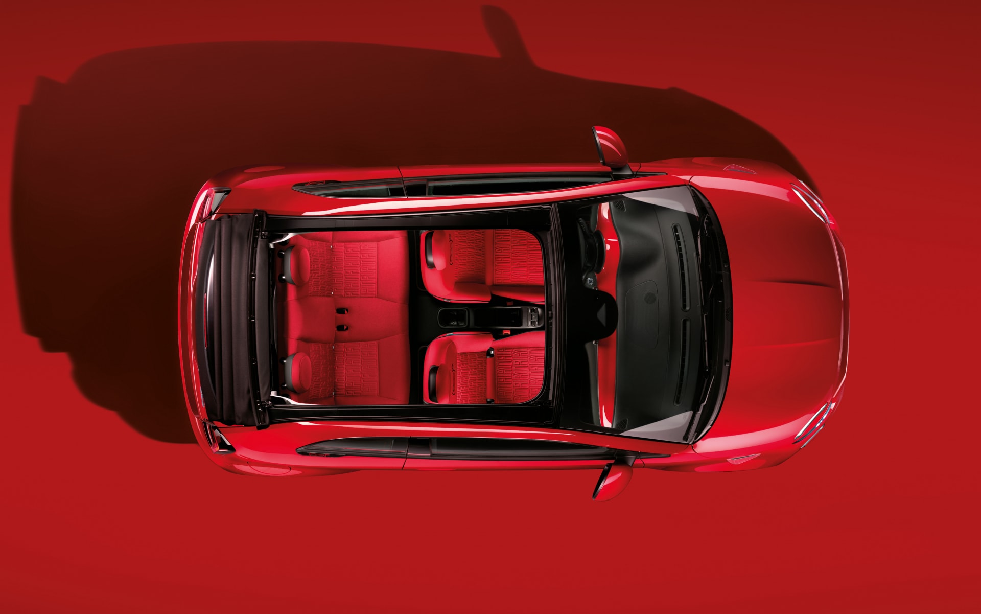 Trasera del Fiat 500e capturada con la arquitectura del aeropuerto de fondo.