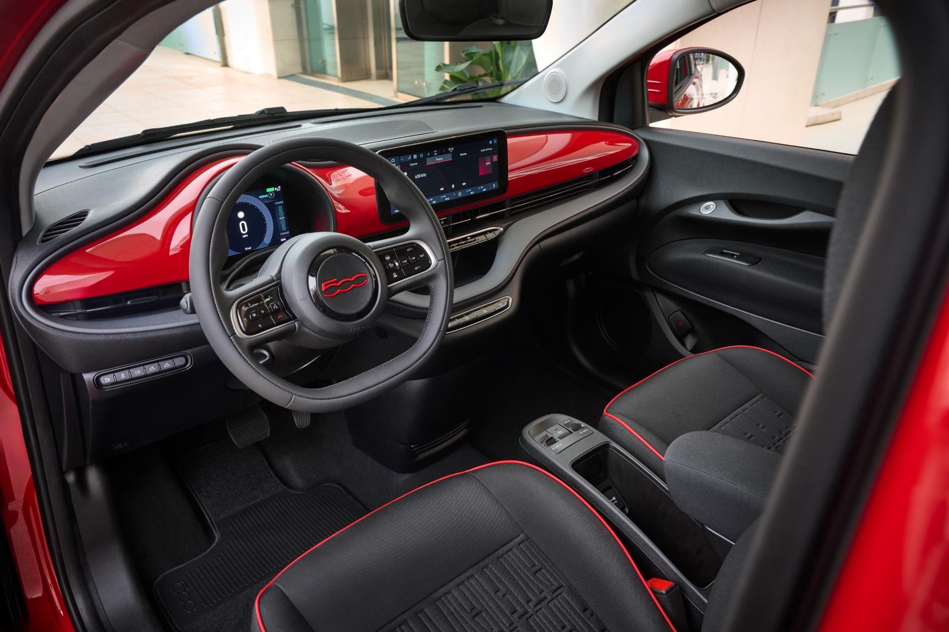 Interior del Fiat 500e con un diseño moderno y detalles en rojo.