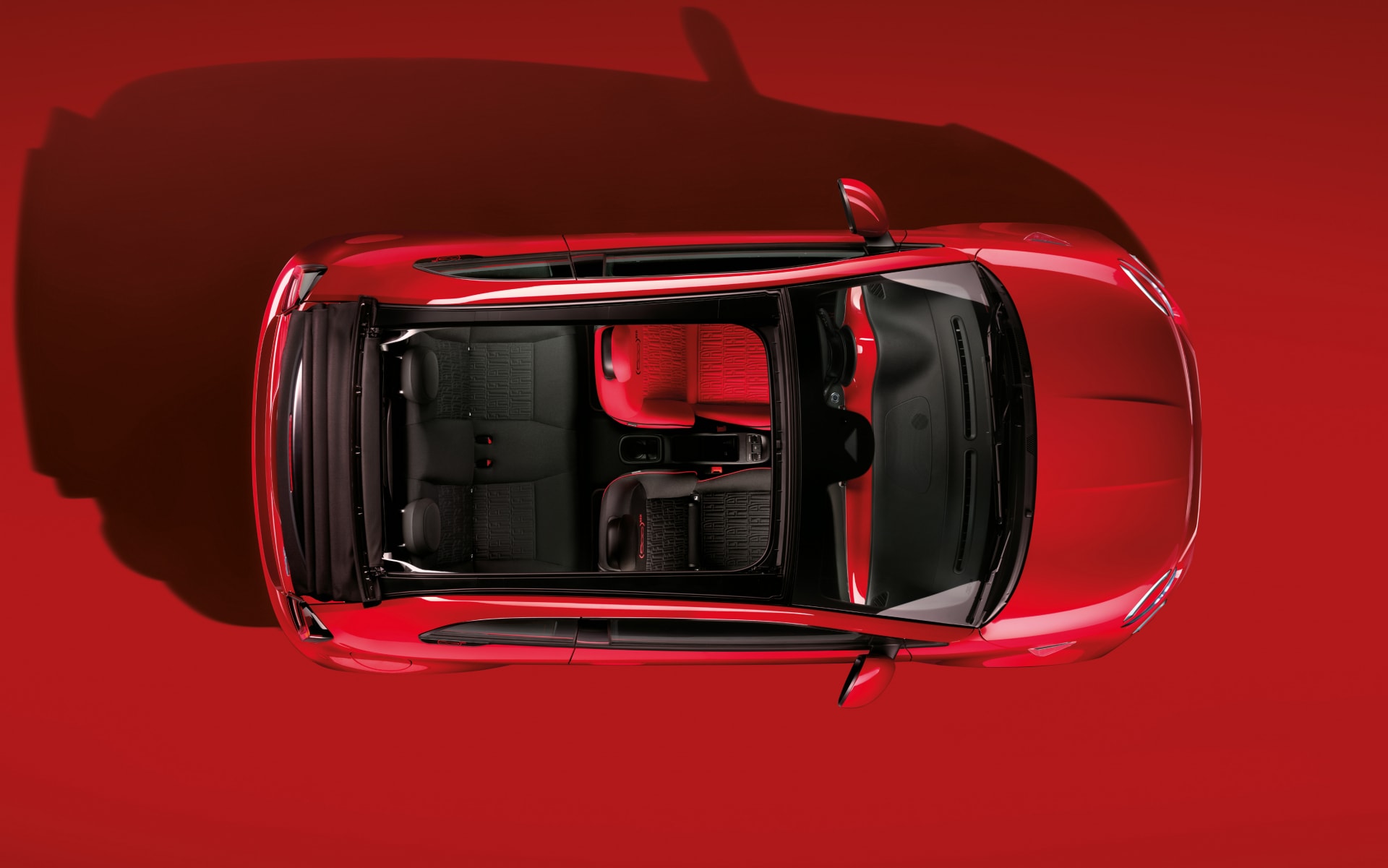 Vista aérea del interior del Fiat 500e, destaca la amplitud y detalle en rojo.