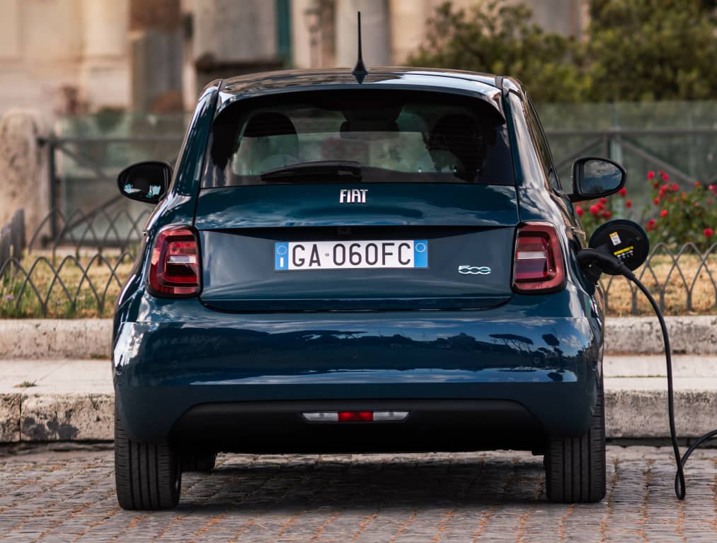 La trasera del Fiat 500e en proceso de recarga, evidenciando su propulsión eléctrica.
