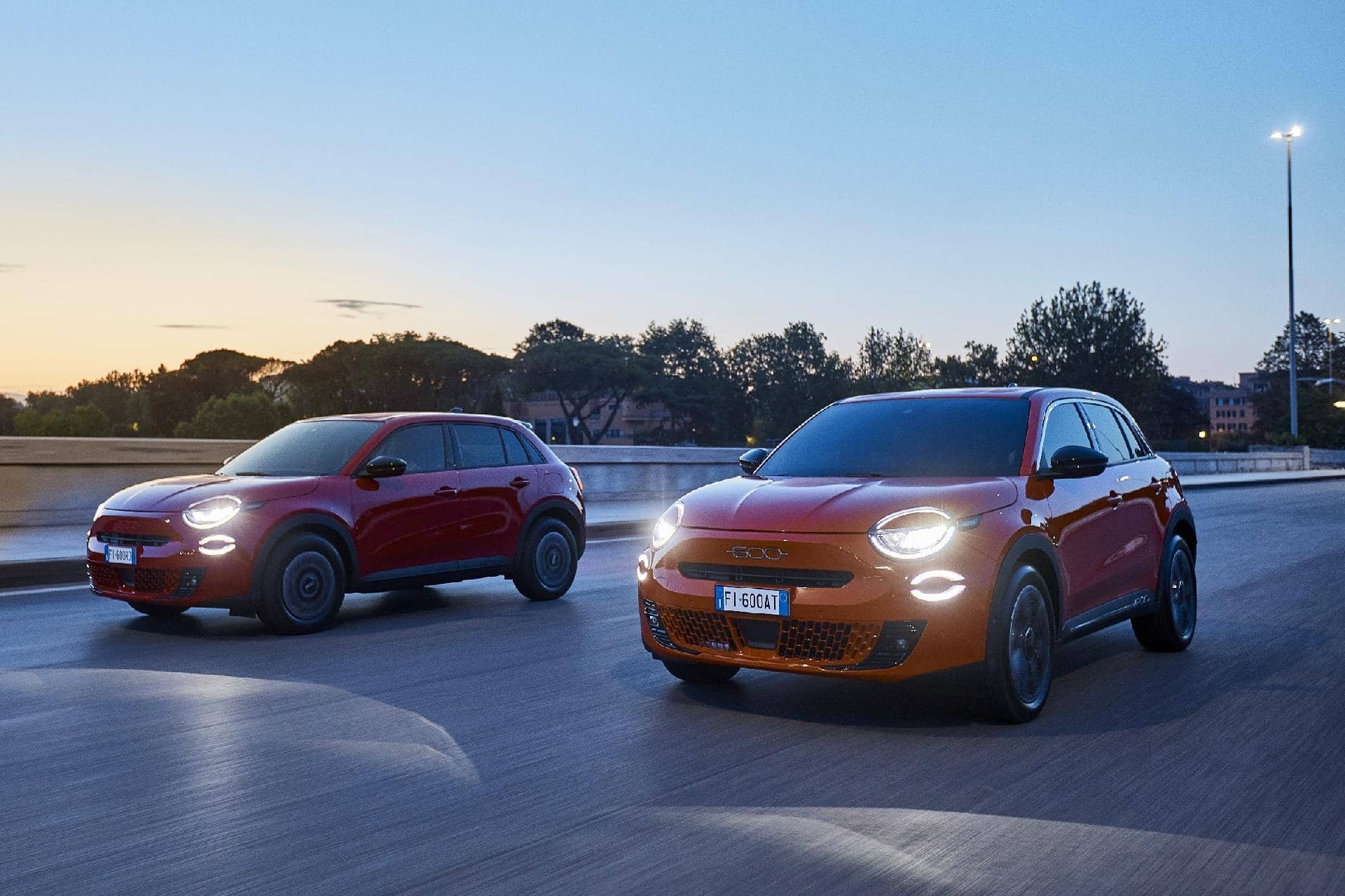 Vista dinámica de dos Fiat 600 en movimiento al atardecer.