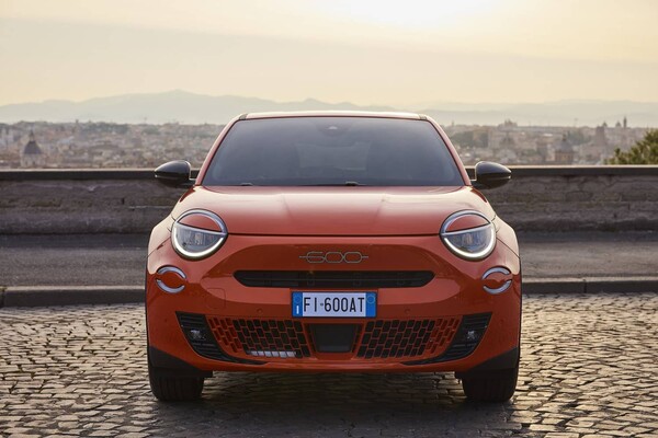 Imagen frontal del Fiat 600e realzando su parrilla y faros en un entorno urbano. Imagen frontal del Fiat 600e realzando su parrilla y faros en un entorno urbano.