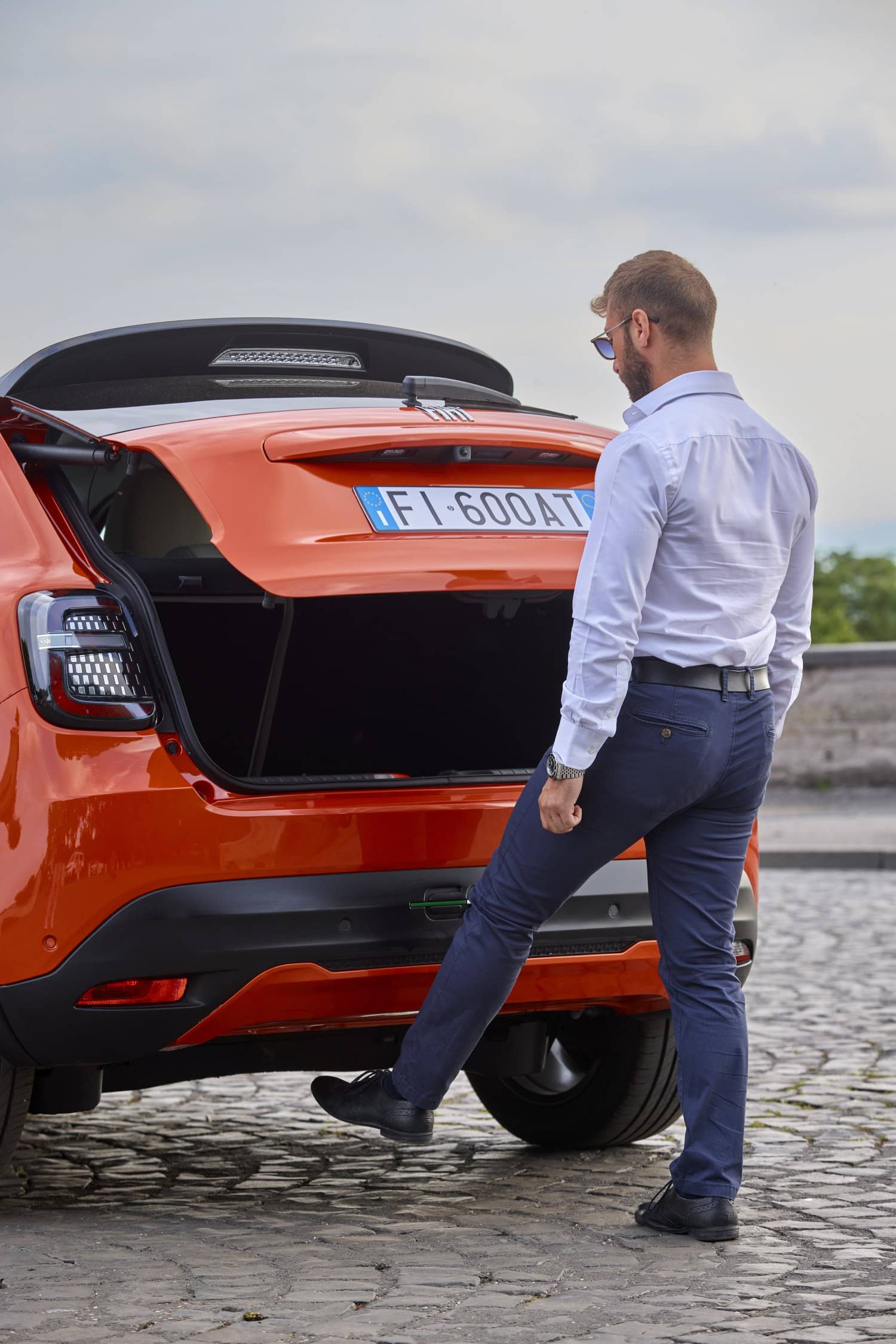Imagen de hombre observando el maletero abierto del Fiat 600e, ideal para evaluar espacio de carga.