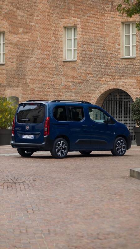 Vista trasera lateral del Fiat Dobló eléctrico estacionado, integrándose en el entorno urbano. Vista trasera lateral del Fiat Dobló eléctrico estacionado, integrándose en el entorno urbano.