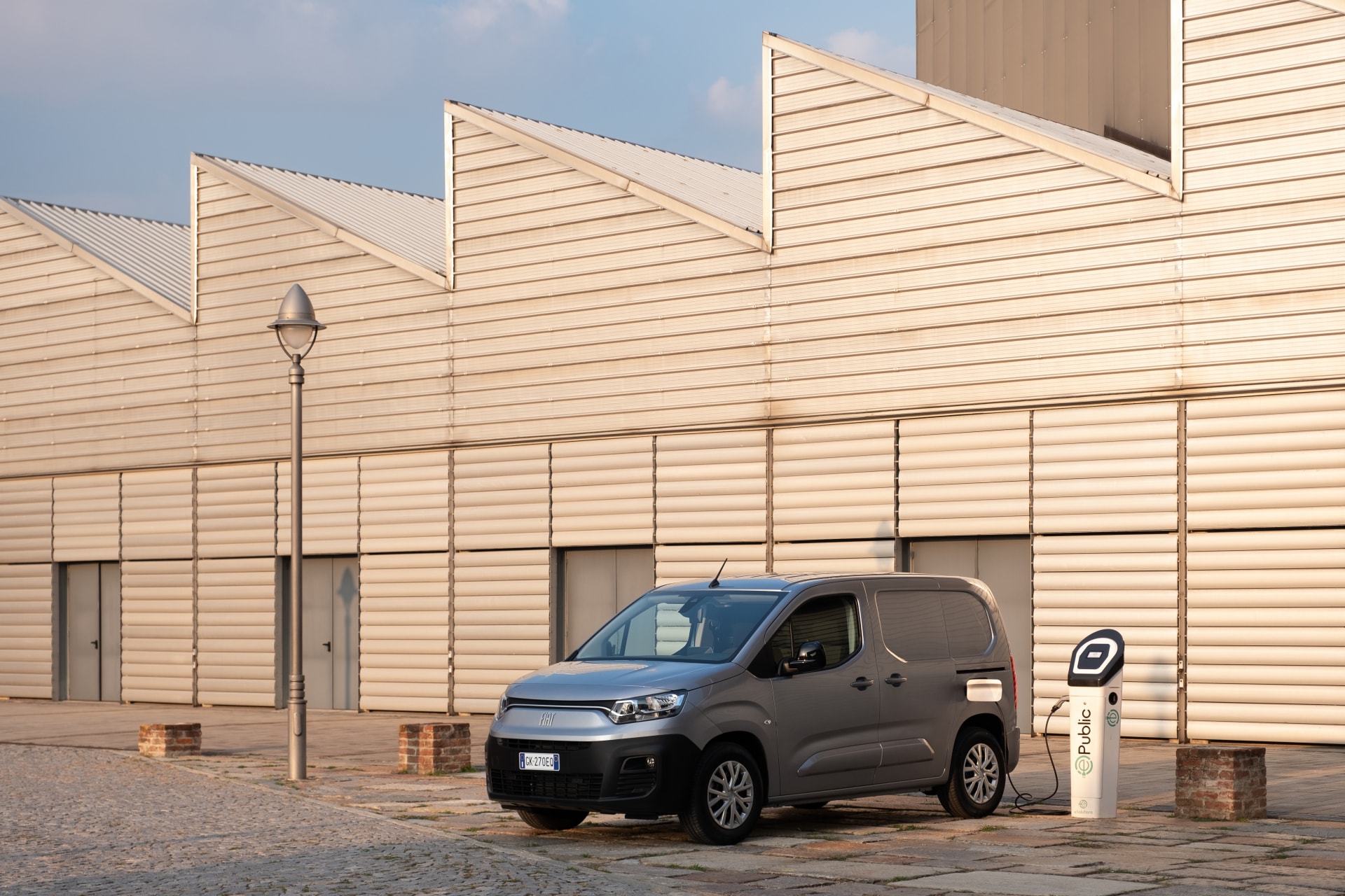 Perfil lateral del Fiat Dobló eléctrico conectado a una estación de carga.