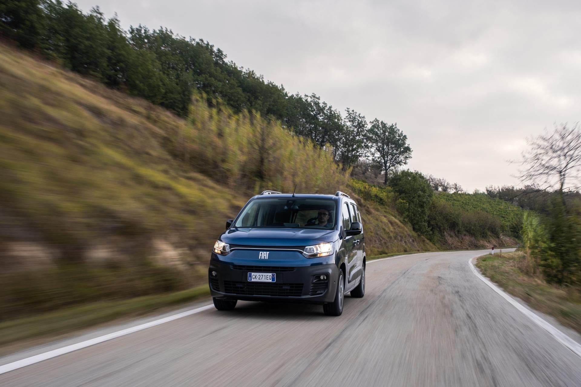 Dinámica imagen del Fiat Dobló eléctrico en movimiento por un camino curvo.