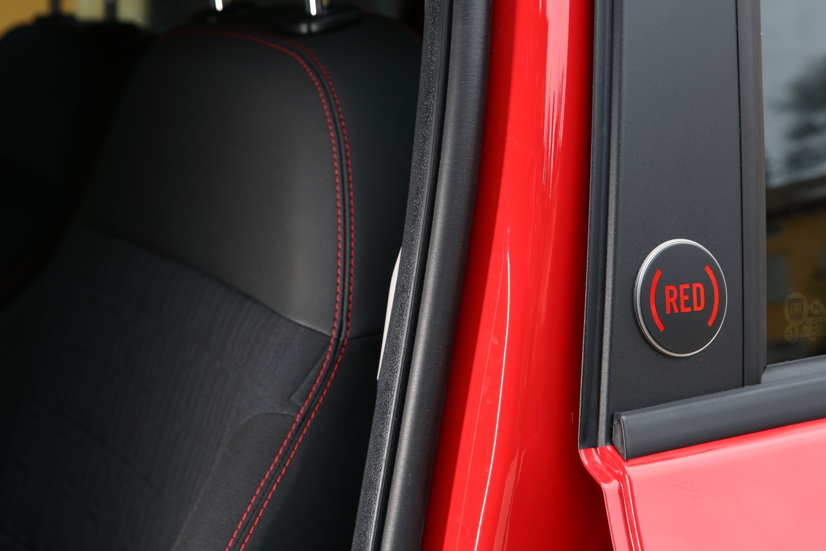 Detalle de la insignia (RED) en los asientos del Fiat Panda, mostrando el compromiso de la marca.