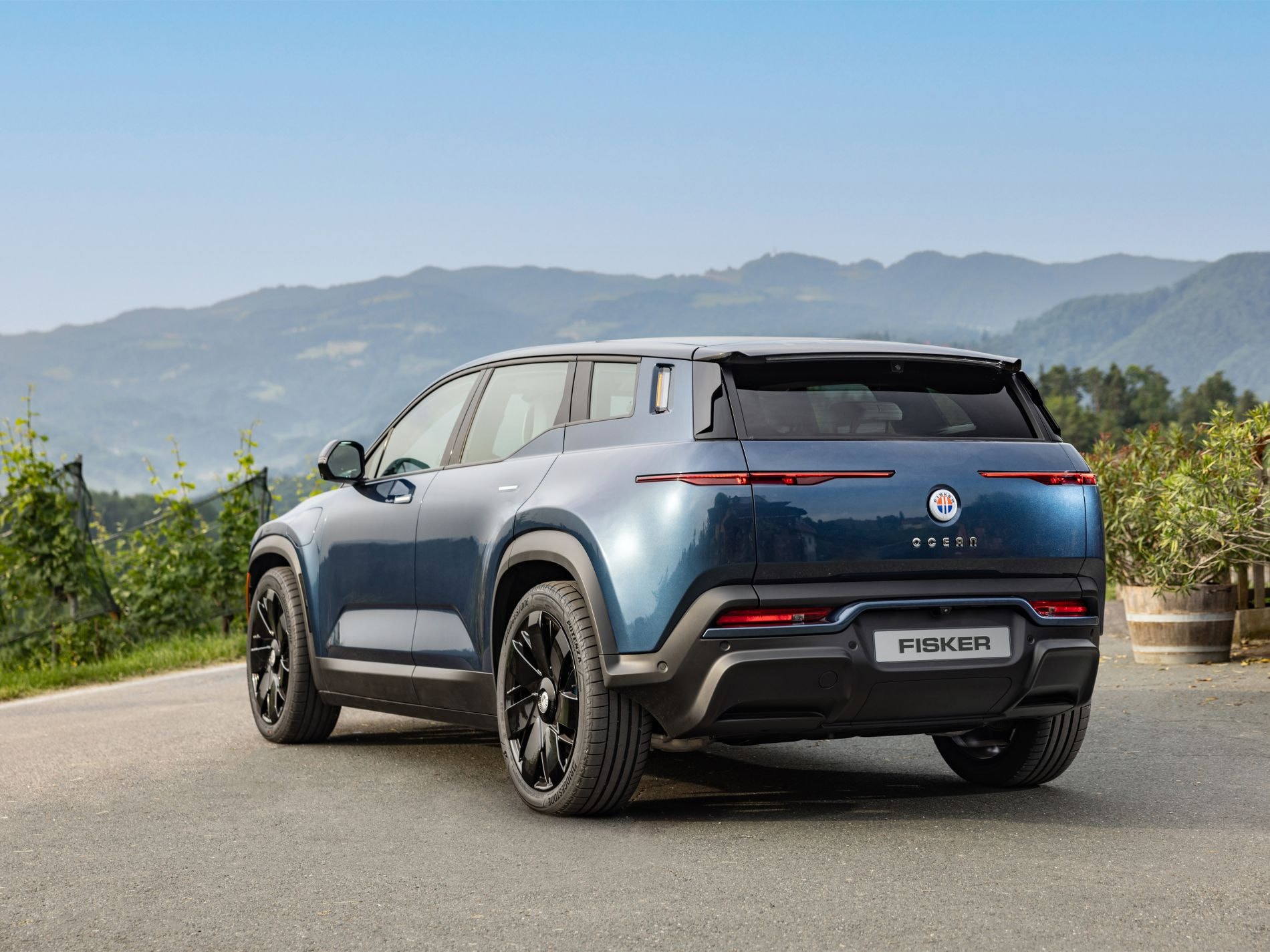 Imagen lateral trasera del Fisker Ocean con montañas de fondo.