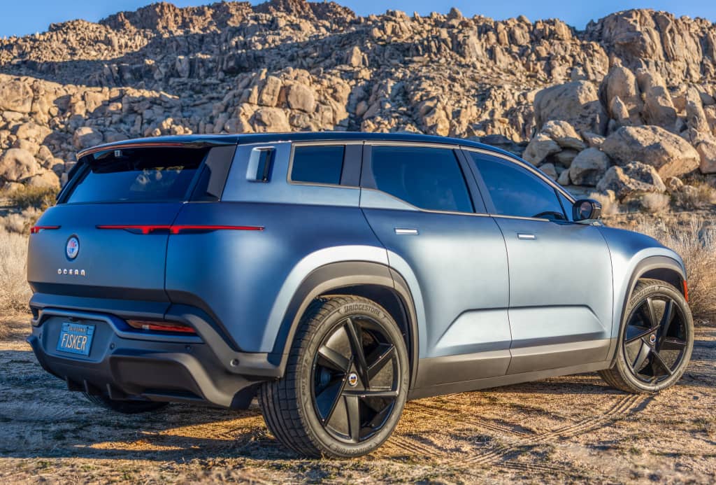 Vista trasera lateral del Fisker Ocean estacionado en la naturaleza.