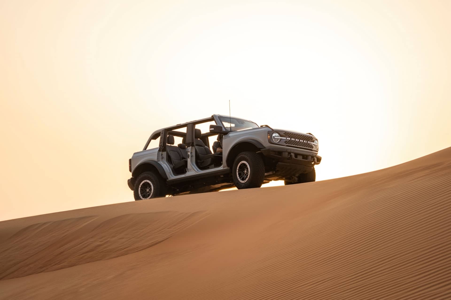 Captura majestuosa del Ford Bronco ascendiendo por una duna.