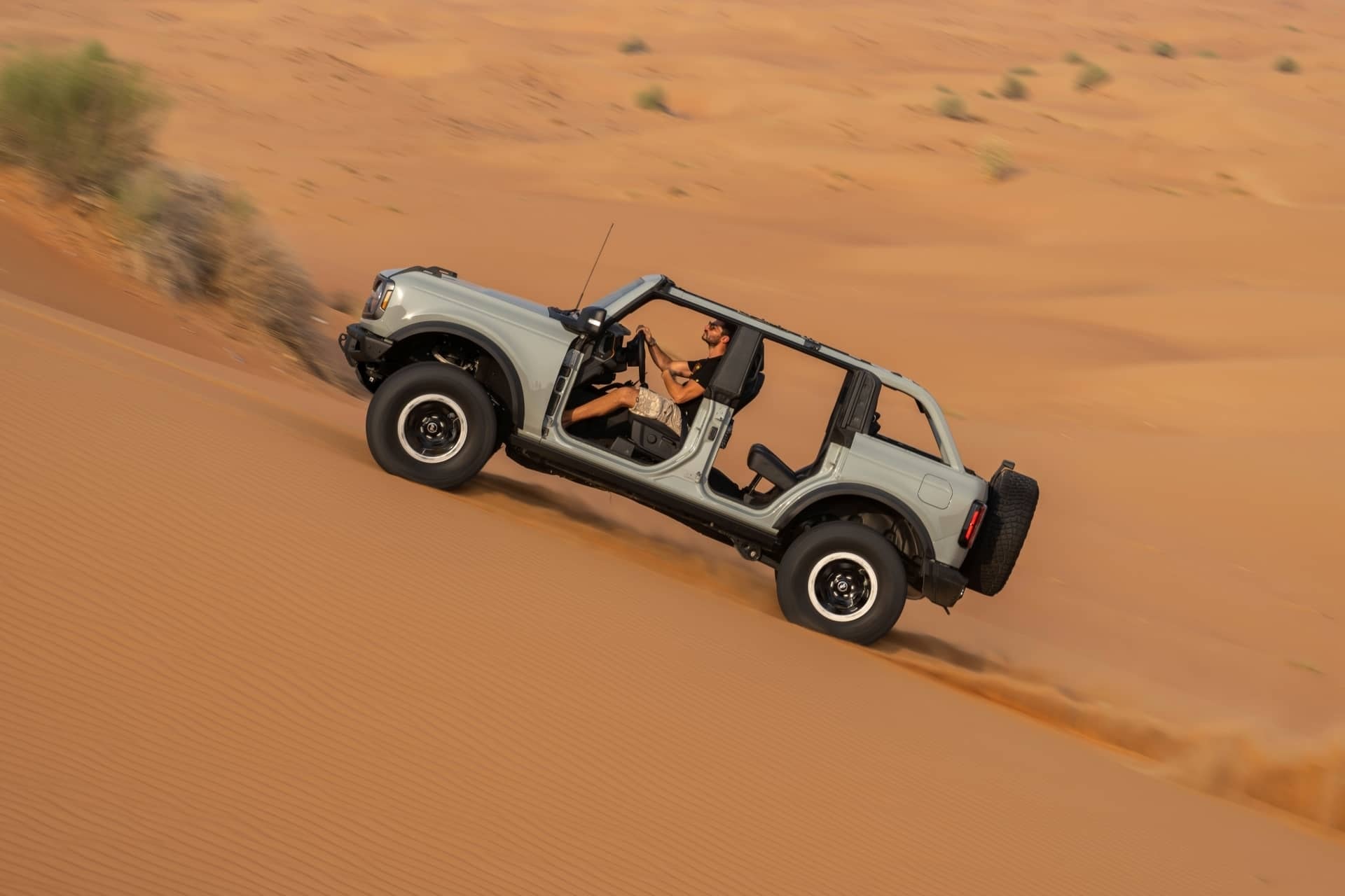 Perfil lateral del Ford Bronco desafiando las dunas del desierto, puertas retiradas.